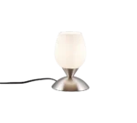 De REALITY Tafellamp CUP II, met een matwitte glazen kap en metalen voet met een zwart netsnoer, staat op een grijs oppervlak tegen een effen grijze achtergrond.
