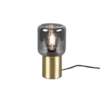 De REALITY Tafellamp NICO heeft een moderne cilindrische koperen voet en een helder glazen kap die een gloeiende gloeilamp onthult. De lamp wordt tegen een witte achtergrond weergegeven en heeft een zichtbaar zwart netsnoer.