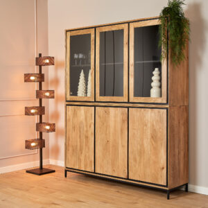 De Vitrinekast RichWood | 160 cm, met glazen bovendeuren en witte decorstukken binnenin, staat naast een moderne staande lamp met vijf houten doosvormige lampen. Een groene plant topt de kast op een lichte houten vloer.