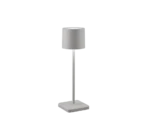 De Reality Tafellamp Fernandez heeft een modern, minimalistisch ontwerp met een cilindrische zilveren lampenkap, dunne steel en rechthoekige voet tegen een witte achtergrond.