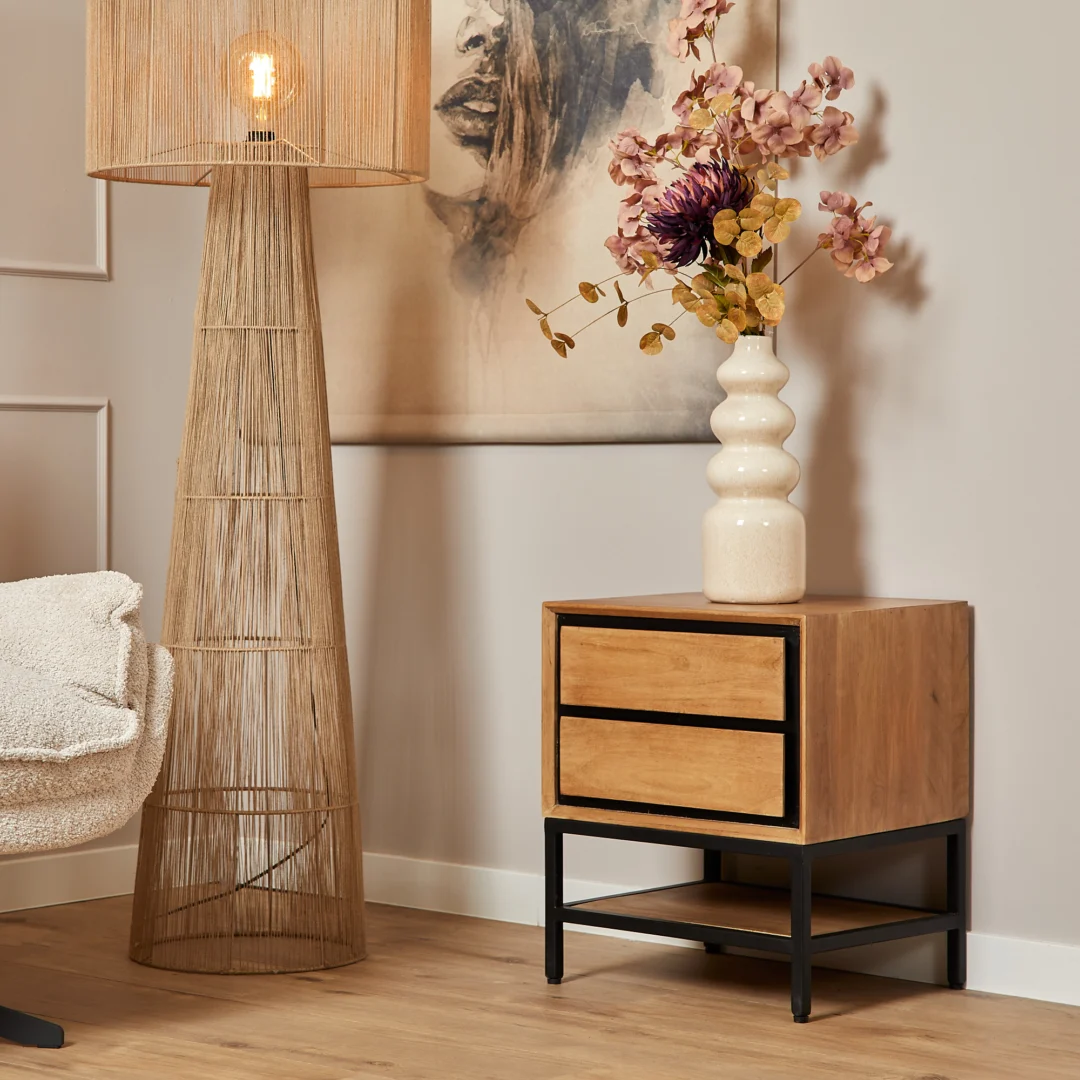 De REALITY Tafellamp MIKI heeft een geometrisch geweven rotan kap in natuurlijke kleur, een zwarte ronde voet en een zichtbare gloeilamp binnenin.