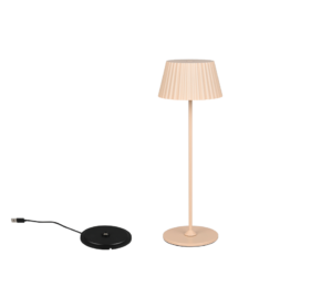 De Reality Tafellamp Suarez, een moderne beige lamp met een geplooide kap, staat naast een zwart rond apparaat met een USB-kabel op een effen witte achtergrond.