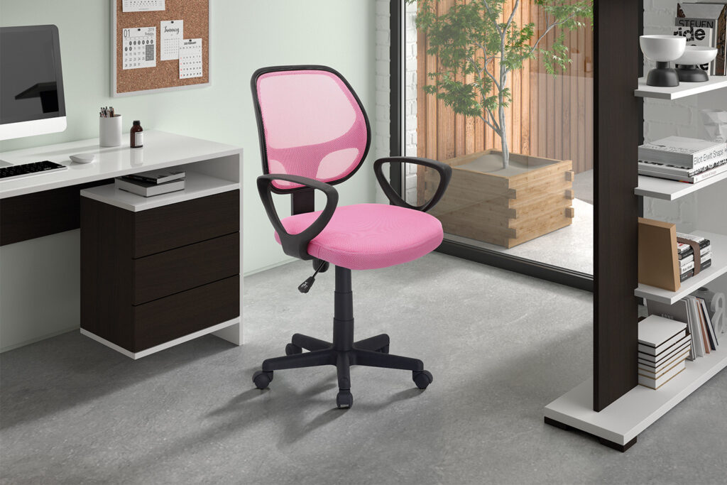De Bureaustoel 'Hippa' Mesh Roze(1c) is een roze bureaustoel van gaas met zwarte armleuningen en wielen, getoond in een modern kantoor aan huis met een wit bureau, boekenplanken en een groot raam met uitzicht op een patio en een groene plant.