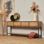 De Sidetable RichWood | 180 cm heeft een modern houten ontwerp met een zwart metalen frame, met daarop een witte vaas met bloemen, decoratieve schijven en een groot vrouwengezicht. Op de onderste plank ligt een rode plaid opgevouwen.