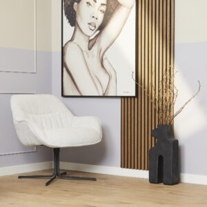 Een moderne leefruimte is voorzien van de Fauteuil Mila Off White stoel, een groot kunstwerk van een vrouw, verticale houten muurlatten en een zwarte sculpturale vaas met takken op een lichthouten vloer.