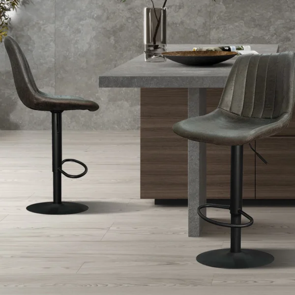 Twee Barstoel 'Barcelona' PU Ote Topper 05 Donkerbruin barkrukken (set van 2) met donkere onderstellen en gestructureerde zittingen staan bij een houten keukeneiland in een minimalistische keuken met lichthouten vloeren, grijze stenen muren en een potplant op de achtergrond.