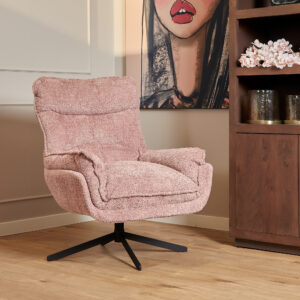 De Fauteuil Vera Roze draaifauteuil staat op een houten vloer naast een versierde boekenplank, met een groot kunstwerk van een vrouwengezicht gedeeltelijk zichtbaar op de muur erachter.