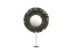 De Mirror On Foot Round Reed Raffia Grey heeft een ronde spiegel met een lijst in sunburst-stijl van donkere, slanke stokjes, gemonteerd op een slanke standaard met een ronde basis, tegen een witte achtergrond.