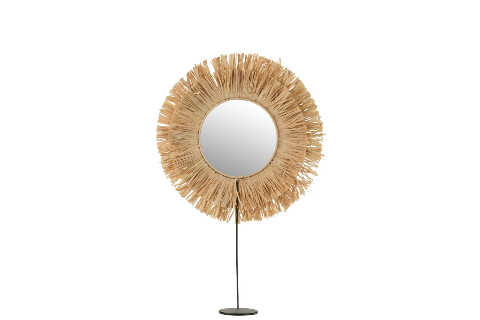 De Mirror On Foot Round Reed Raffia Natural heeft een rond glazen oppervlak met een frame in sunburst-stijl van natuurlijke raffia, op een zwarte metalen standaard met een ronde basis, tegen een witte achtergrond.