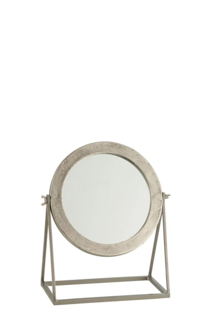 De Mirror Round On Foot Metal Silver heeft een metalen frame met textuur, een verstelbare ronde spiegel met scharnieren aan de zijkant en een metalen standaard met driehoekige voet. Perfect voor elke ruimte, gefotografeerd tegen een witte achtergrond.