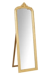 De staande spiegel Emi Wood Gold Colored heeft een sierlijke gouden lijst met een decoratieve kuif aan de bovenkant en wordt ondersteund door een achterstandaard.