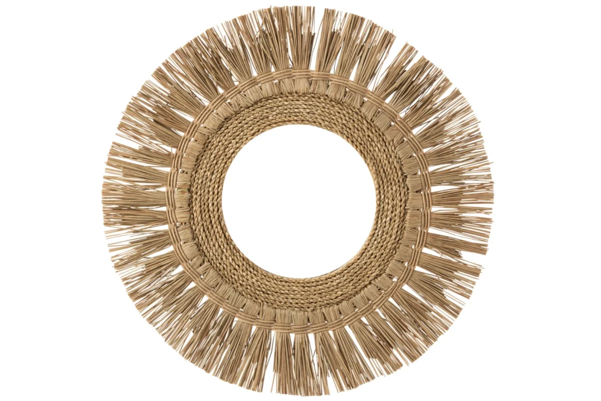 De Mirror Round Grass Natural heeft een brede, decoratieve lijst van gevlochten en gefranjerd natuurlijk gras in een zonnestraalpatroon. Het spiegelende midden is niet zichtbaar in deze afbeelding.