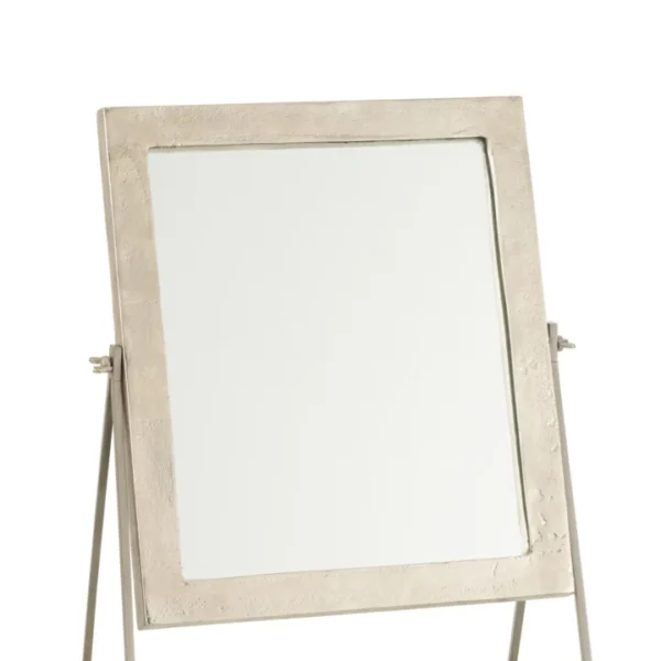 De Mirror Square On Foot Metal Silver heeft een vierkante metalen lijst met textuur, gemonteerd op een metalen standaard met een geometrische driehoekige basis om te kantelen. Afgebeeld tegen een effen witte achtergrond.