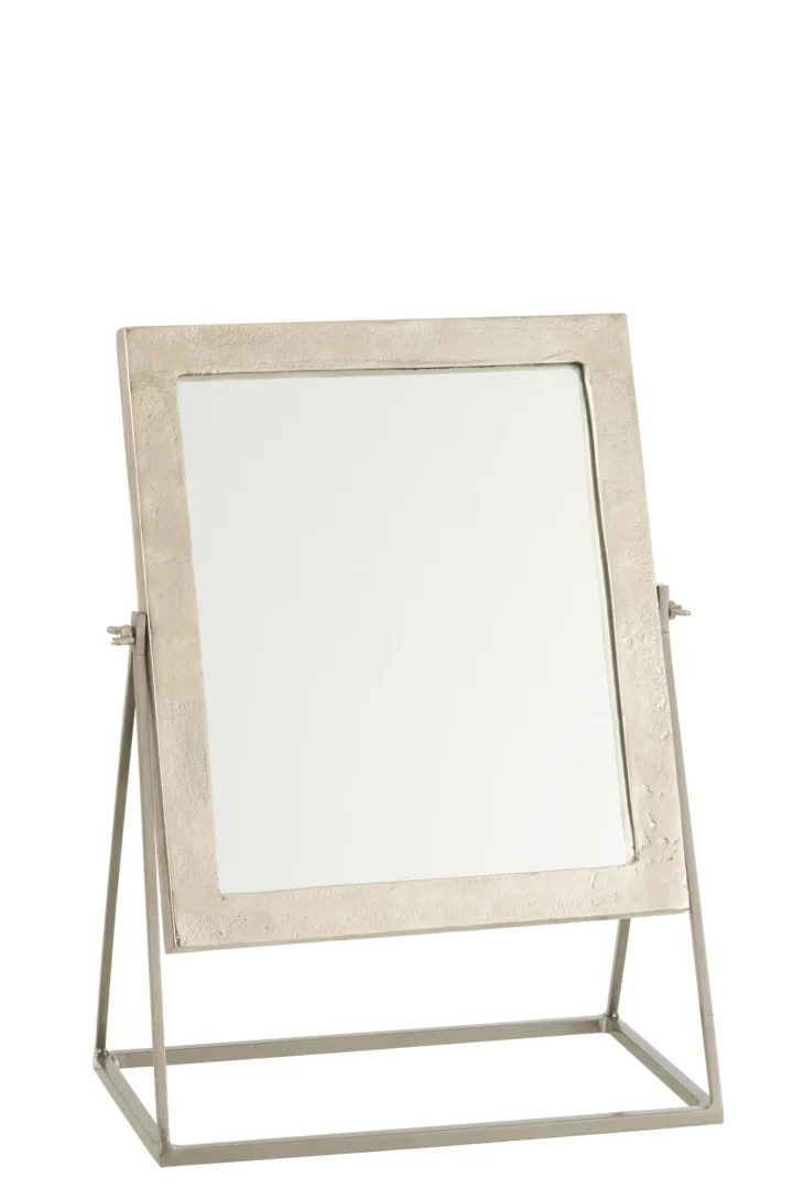 De Mirror Square On Foot Metal Silver heeft een vierkante metalen lijst met textuur, gemonteerd op een metalen standaard met een geometrische driehoekige basis om te kantelen. Afgebeeld tegen een effen witte achtergrond.