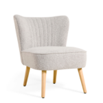 De Fauteuil Vive - Bouclé Naturel heeft een moderne lichtgrijze bouclé bekleding, een gebogen rug met verticale stiksels en vier lichte houten poten tegen een witte achtergrond.