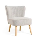 De Fauteuil Vive - Bouclé Naturel heeft een moderne lichtgrijze bouclé bekleding, een gebogen rug met verticale stiksels en vier lichte houten poten tegen een witte achtergrond.