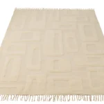 De Vloerkleed Abstracte Lijnen Wol Ecru is een beige rechthoekig vloerkleed met een geometrisch verhoogd patroon van rechthoeken en ovalen, met franjes aan de korte zijden.