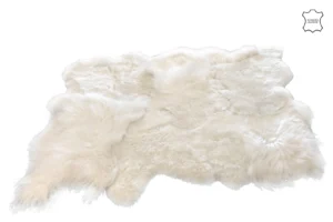 Het Vloerkleed Schaap Wit Groot is een grote, zachte off-white schapenvachtdeken met pluizige, ongelijke randen en een mix van lang en kort bont, plat neergelegd op een witte achtergrond met een echt lederen symbool in de hoek.