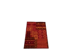 Vloerkleed Afrikaans Polyacryl Mix Klein is een rechthoekig, veelkleurig tapijt met een patchworkontwerp in rood, oranje en bruin, met geometrische en tribale patronen. Het wordt getoond op een witte achtergrond.