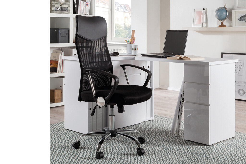 In een modern kantoor aan huis zit de Bureaustoel 'Max' Mesh Zwart aan een wit bureau met een laptop, een open boek en een kopje. Planken met boeken en decor staan op de achtergrond op een lichtgekleurd tapijt.
