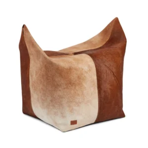 De Kalfslederen Poef Klein Groot KG04 is een vierkante voetenbank met spitse hoeken, bekleed met bruin en wit koeienhuid voor een zachte, ontspannen uitstraling.