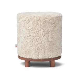 De Simon Kruk Korte Wol A is een ronde, crèmekleurige, donzige voetenbank met een houten basis en drie korte poten, afgebeeld tegen een witte achtergrond.
