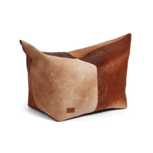 De Kalfslederen Poef Klein Groot KG02 is een grote rechthoekige zitzakstoel, bekleed met patchwork koeienhuid met lichtbeige, bruine en roodbruine delen voor een natuurlijke, rustieke stijl.