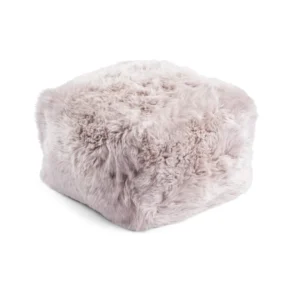 De Poef Schapenvacht Lange Wol L06 is een zachte, vierkante poef met lichtroze, pluizige bekleding van imitatiebont, afgebeeld tegen een witte achtergrond.