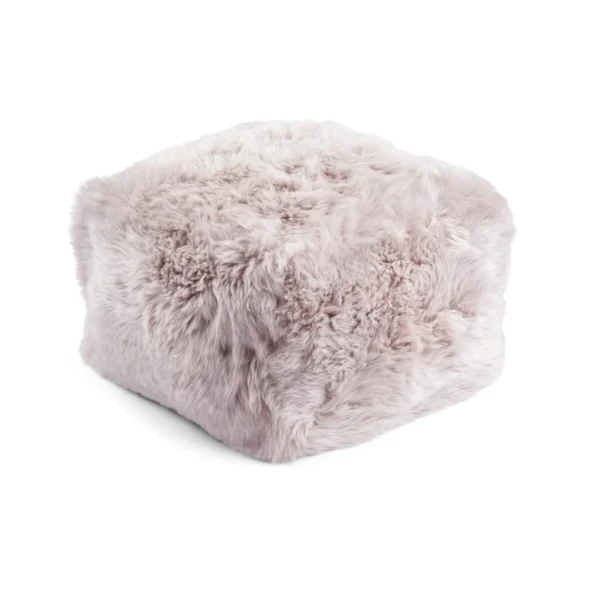 De Poef Schapenvacht Lange Wol L06 is een zachte, vierkante poef met lichtroze, pluizige bekleding van imitatiebont, afgebeeld tegen een witte achtergrond.