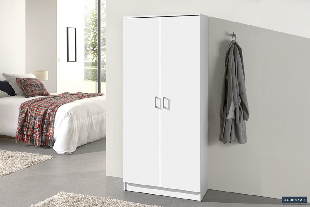 Een moderne slaapkamer met de Opbergkast 'Ray' 2 deuren en 4 legplanken Wit (1c) tegen de muur, een grijze badjas aan een haak in de buurt en een bed met een geruite deken bij het raam.