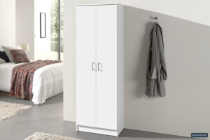 De Opbergkast 'Ray' met 2 deuren en 4 legplanken in wit staat tegen de muur in een moderne slaapkamer. Naast de kast hangt een grijze badjas aan een haak. Op de achtergrond zie je een bed met geruit dekbed.