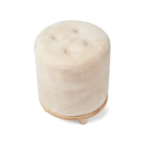 De Simon Kruk Moccasin A is een ronde, beige poef met een getufte bovenkant, houten basis en korte houten poten, afgebeeld op een witte achtergrond.