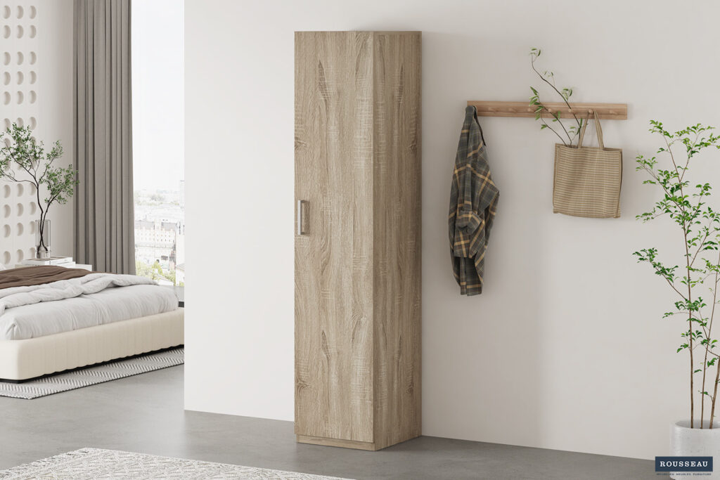 Een moderne slaapkamer met de Opbergkast 'Mike' 40 cm 1 deur Sonoma, een wandhaak met een geruit overhemd en gestreepte tas, planten en een bed met wit beddengoed bij een groot raam.