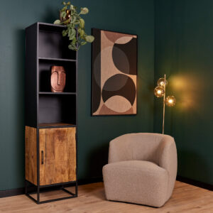 Een moderne leefruimte met een groene muur, de Boekenkast Oakland | 50 cm hoge kast van zwart en hout met een plant en decor, een abstract kunstwerk, een beige gebogen fauteuil en een vloerlamp met drie ronde lampen.