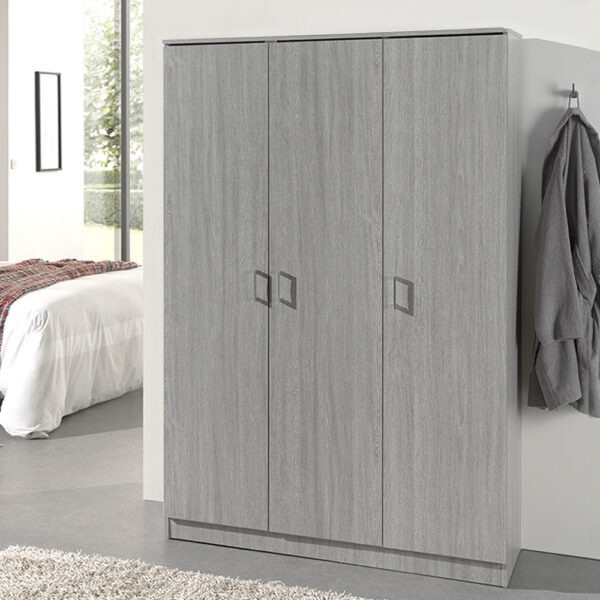 Een moderne slaapkamer is voorzien van de Opbergkast 'Ray' 3 deuren en 4 legplanken Grijze eik kledingkast, een grijs gewaad aan de muur, een bed met wit beddengoed en geruite deken, en een raam dat natuurlijk licht binnenlaat.