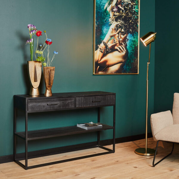 Een moderne woonkamer met de Sidetable Denver Zwart met 2 laden, gouden vazen met bloemen, een gouden staande lamp, een abstract portret op een groene muur en een beige stoel op een lichte houten vloer.