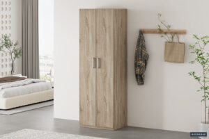 Een minimalistische slaapkamer is voorzien van de Opbergkast 'Mike' 60 cm 2 deuren Sonoma, een houten wandrek met een geruit overhemd en tas, een bed met wit beddengoed, potplanten en natuurlijk licht door een groot raam.