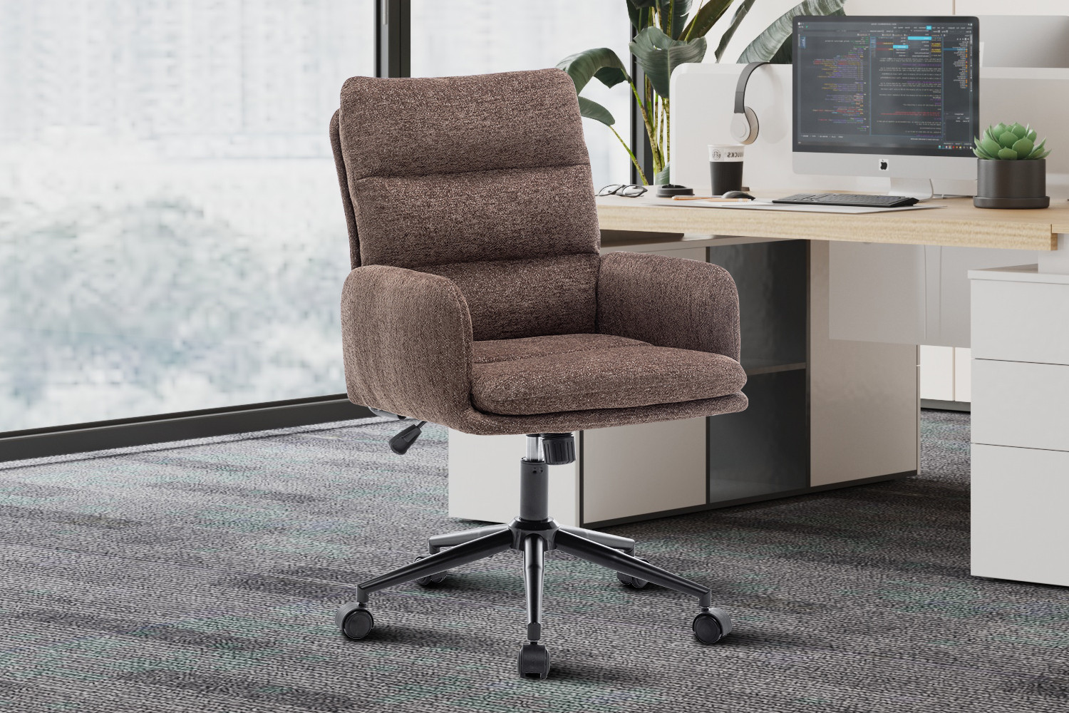 De Bureaustoel 'Aimé' Stof Fabb Raven 45 Bruin staat voor een modern wit bureau met een computer, planten en kantoorartikelen in een lichte werkruimte met vloerbedekking.