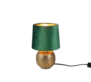 De REALITY Tafellamp SOPHIA heeft een kleine ronde, goudkleurige voet met textuur en een donkergroene fluwelen lampenkap. Wanneer de lamp brandt, geeft ze een warme gloed. Een zwart snoer komt uit de lampvoet.