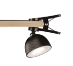 De REALITY Tafellamp MAXIMA is een moderne zwarte klemlamp met een geribbelde kap die op een houten oppervlak wordt geklemd en licht naar beneden werpt.