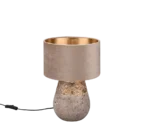 De Reality Tafellamp Kiran heeft een beige fluwelen lampenkap, een gestructureerde stenen voet met gouden bloemmotieven en een zichtbaar zwart elektriciteitssnoer.