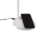 Een zwarte smartphone staat op de voet van de Reality Tafellamp Load, een witte bureaulamp die wordt aangedreven door een zwart snoer.