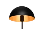 De TRIO Tafellamp Nola heeft een modern ontwerp met een zwarte koepelvormige lampenkap en straalt een zacht warm licht uit tegen een effen zwarte achtergrond.