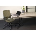 Een modern kantoor is voorzien van de Workliving Eva Comfort Groen Regain ergonomische stoel, een grijze tafel met een laptop, draadloze muis, kop en schotel, potplant en minimalistisch decor op een zwarte vloerbedekking.