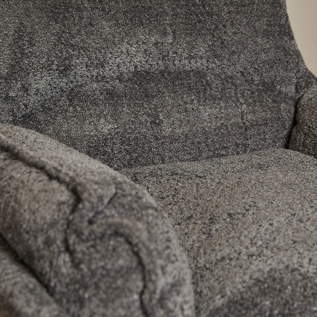 Close-up van de Fauteuil Vera donkergrijze fauteuil, met de pluche bekleding met textuur en een zachte, knusse zitting, armleuning en rugleuning.