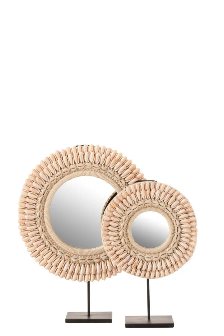 Twee "Mirror On Foot Mona Shells Light Pink Large" ronde spiegels met schelpenlijst, elk op een zwarte metalen standaard. De grotere spiegel staat achter en links van de kleinere.