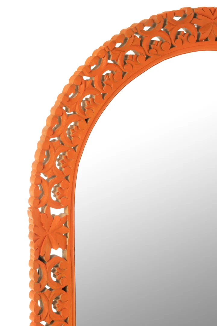 Close-up van de linkerbovenhoek van de Mirror Carved Mumbai Mango Wood Mix, met een sierlijke oranje gebeeldhouwde bloemenlijst tegen een witte achtergrond.
