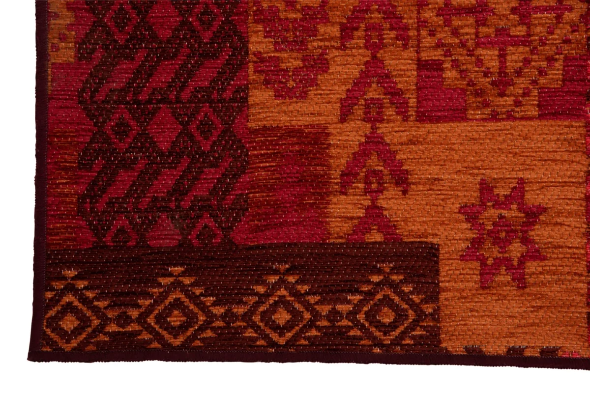 Een close-up van het Vloerkleed Afrikaans Polyacryl Mix Groot tapijt toont geometrische en florale patronen in rood, oranje en bruin, met diamanten, zigzag en stervormen die de rand en het hoofdontwerp versieren.