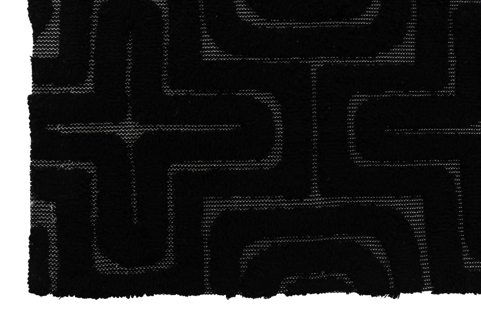 Een close-up van Vloerkleed Reliëf Viscose Zwart toont de zwarte structuurstof met een verhoogd geometrisch patroon van kruisende lijnen en rondingen, en een rand met franjes die gedeeltelijk zichtbaar is aan de linkerkant.