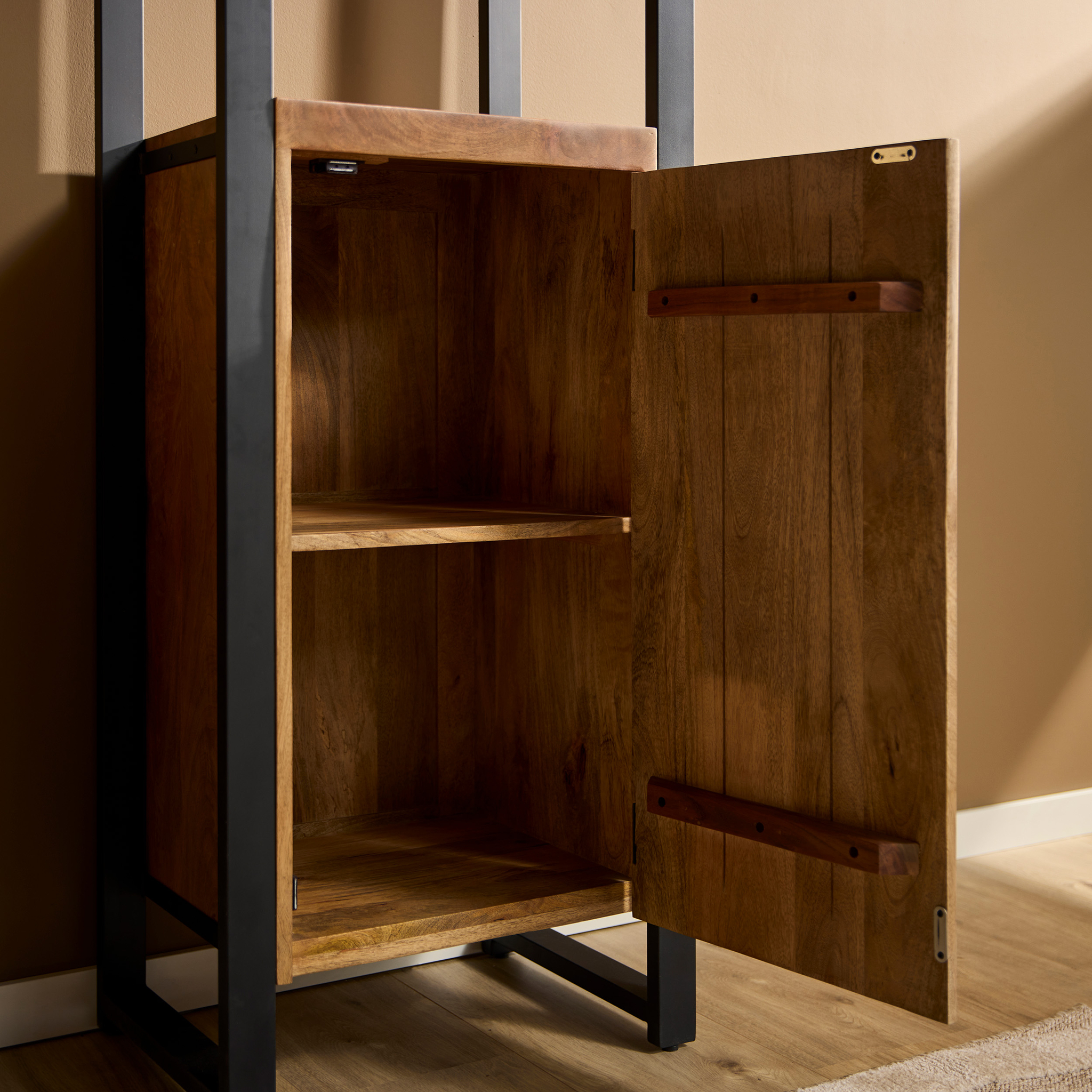 Boekenkast Boaz | 1 deur heeft een houten kast met een metalen frame, open om twee lege planken te tonen. Het staat op een houten vloer tegen een bruingekleurde muur.